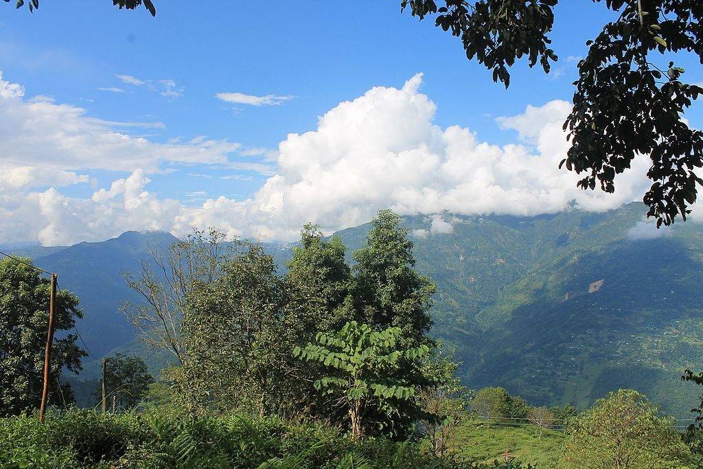 Green mountains around Kolakham under a clear blue sky