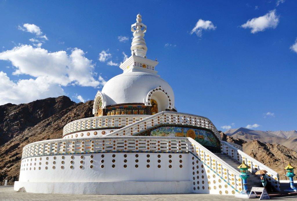 Shanti Stupa at Leh under a clear blue sky with white clouds floating around