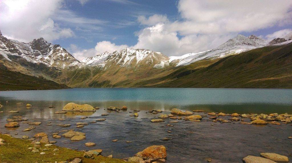 Clear waters of Gangabal Lake surrounded by snow capped mountains