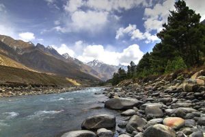 Baspa River flowing through Chitkul valley with white cloud patches in the blue sky