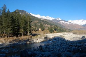 Beas river flowing through Manali valley with snow capped mountains in the background