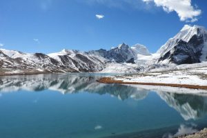 Reflection of mountains on the clear blue water of Gurudongmer lake under a clear blue sky