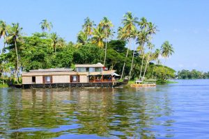 Under a blue sky and sunny day, house boat plying in the backwaters of Kerala