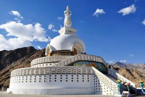 Shanti Stupa at Leh under a clear blue sky with white clouds floating around