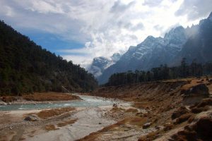 River flowing through the Yumthang Valley with snow covered mountains in the back